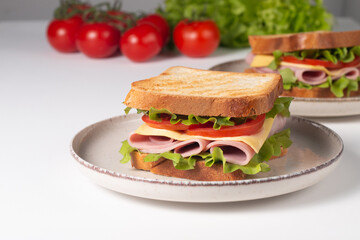 Close-up of two sandwiches with bacon, salami, prosciutto and fresh vegetables on rustic wooden cutting board. Club sandwich concept - 752431314