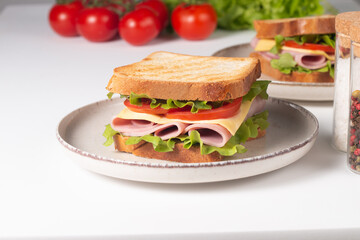 Close-up of two sandwiches with bacon, salami, prosciutto and fresh vegetables on rustic wooden cutting board. Club sandwich concept - 752431343