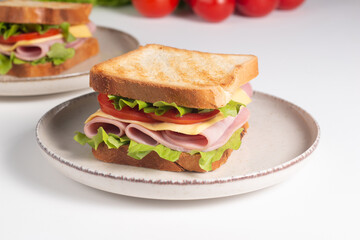 Close-up of two sandwiches with bacon, salami, prosciutto and fresh vegetables on rustic wooden cutting board. Club sandwich concept - 752431354