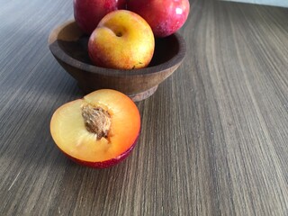 Naklejka na ściany i meble Red plum in bowl on a wooden background with copy space ​