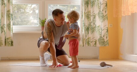 Interaction between father and son involves playfully bumping foreheads, reflecting moment of...