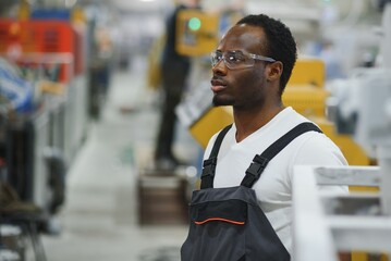 Industrial worker indoors in factory. Young technician with orange hard hat