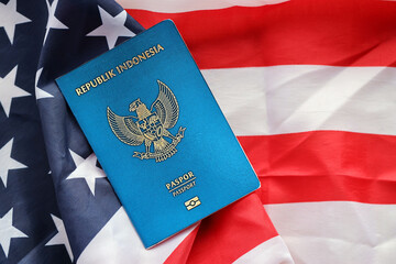 Naklejka premium Blue Republic Indonesia passport on United States national flag background close up. Tourism and diplomacy concept