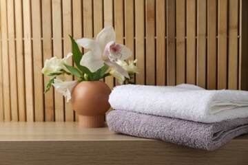 Terry towels and beautiful flowers on wooden table