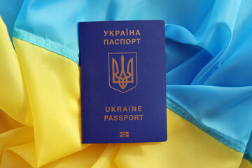 One Ukrainian biometrical passport on folded waving flag of Ukraine country close up