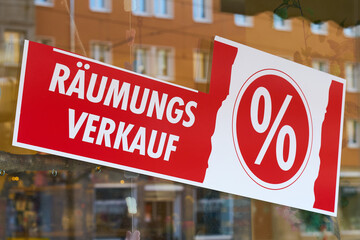 Schild mit der deutschen Aufschrift Räumungsverkauf vor Geschäftsschließung an einem Schaufenster