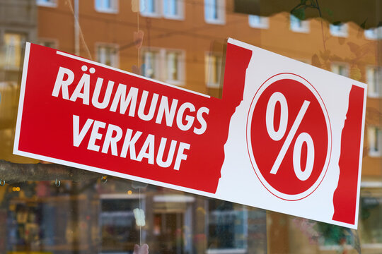 Schild mit der deutschen Aufschrift R&auml;umungsverkauf vor Gesch&auml;ftsschlie&szlig;ung an einem Schaufenster