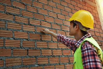 The professional technician inspects brick walls of commercial buildings.
