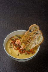 Cheese soup with croutons and veggies on a black background