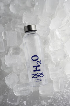 Refrescante botella de agua cayendo sobre hielo