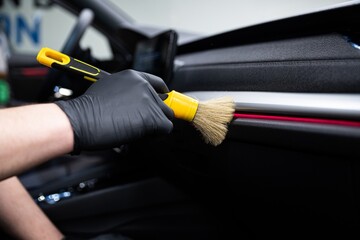 Car wash or car detailing studio worker carefully cleaning car interior with special brush  - 752456300