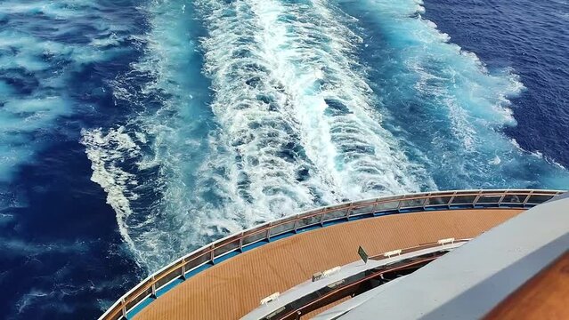 Rear side of a cruise ship showing frothy waves created by its engine