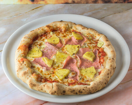 Tropical Hawaiian pizza with pineapple slices and ham on a baked dough base served whole with copyspace