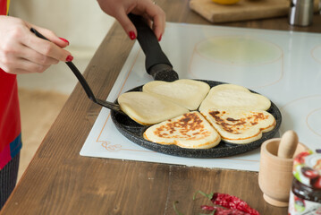 Heart-shaped pancake pan in a bright kitchen. The process of making pancakes and using a frying pan