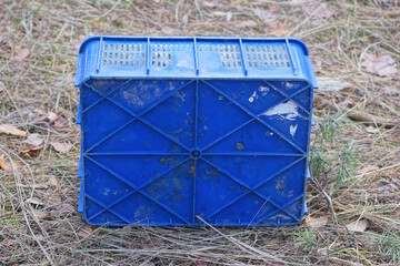 one old blue plastic box stands on the gray ground on the street
