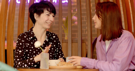 Dialogue and Active Listening: Two women converse in a cafe setting. Woman engages in conversation...