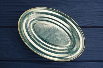 one closed aluminum gray yellow oval tin can lies on a black table