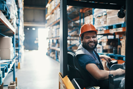 Smiling male forklift operator working in warehouse
