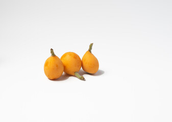 three ripe loquats on a white background.