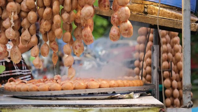 Saigrok Isaan Sausages being cooked on the grill in outdoor market. Traditional Thai street food concept