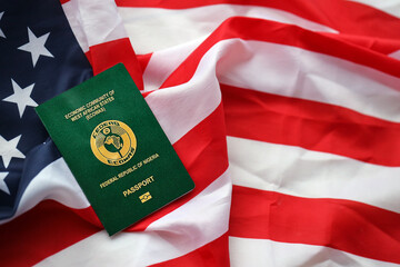 Green Nigerian passport on United States national flag background close up. Tourism and diplomacy...