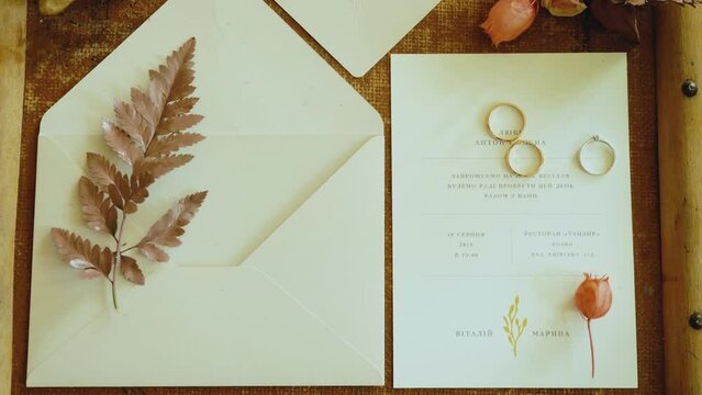 Romantic wedding set invitation with intricate design on paper, rings on table