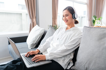 Asian woman in casual clothes, wearing headphone to listening music and chatting with friend in...