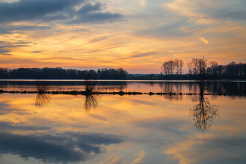 Colorful sunset reflected in the lake at the Geestmerambacht recreational area. The clouds above the Geestmerambacht recreational area are beautifully illuminated by the setting sun. 