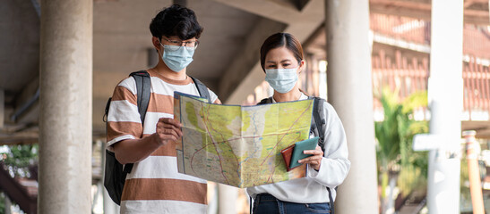 Tourist couple with luggage looking on the map to searching direction destination for honeymoon trip