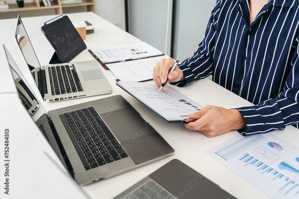 Poster Business man trader checking statistics graph on laptop and statistics data on document to analyze about stock market
