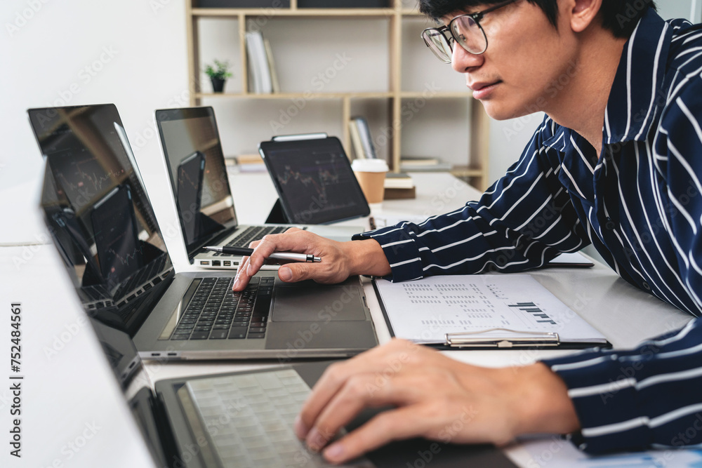 Poster Business man trader using laptop to checking stock market online and looking statistics graph on laptop to analyze