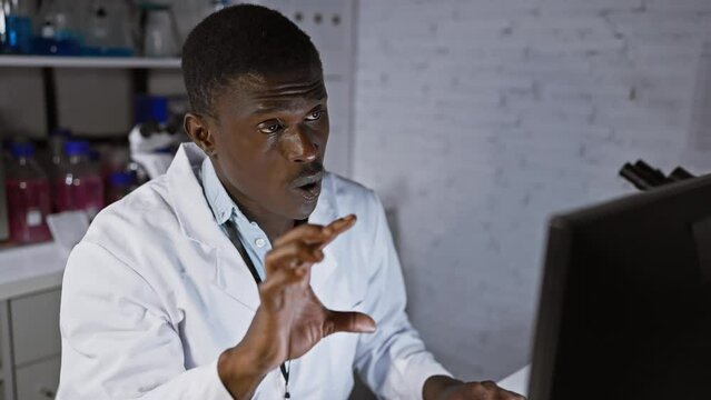 Focused black man analyzing data on a computer screen in a modern laboratory setting