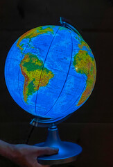A child curious about the world holds an illuminated globe in his hands