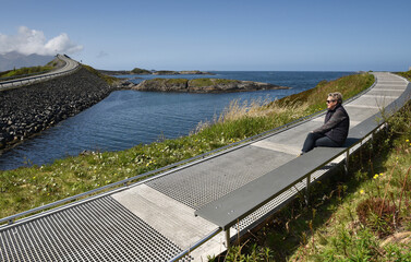 Frau sitzt in einer Schärenlandschaft an der Atlantikstraße in Norwegen	