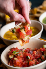 Woman dips chip in salsa