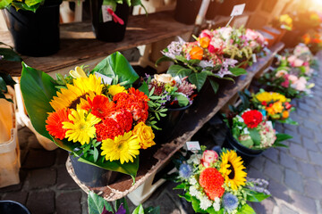 Many colorful array of fresh flower bouquets on display at an outdoor street city market on warm spring sunny day. Bright blossoming plants retail store at Bremen Germany - obrazy, fototapety, plakaty