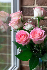 Pink roses by the window. Reflection of flowers in the window. Festive bouquet