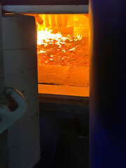 Burning coal and slag on a mechanical grate visible through the open hatch of a coal-fired grate...