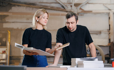 Young woman designer and man carpenter are discussing wooden furniture for kitchen project at...