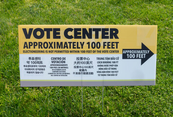 A multilingual voting center sign with arrow and instruction