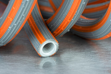 Rubber garden water hose on wet metal surface, close-up