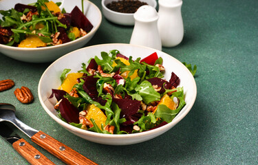 Salad with arugula, orange and beet in a plate on a green background - 752521508