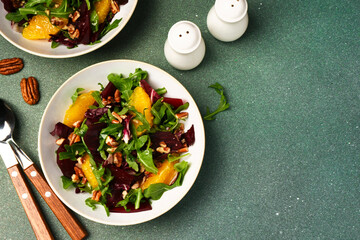 Salad with arugula, orange and beet in a plate on a green background - 752521532