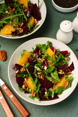Salad with arugula, orange and beet in a plate on a green background - 752521562