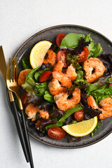 Salad with shrimp and tomatoes in a plate on the white background with space for text on a white background.
