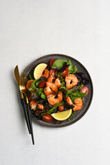 Salad with shrimp and tomatoes in a plate on the white background with space for text on a white background.