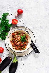 Salsa with eggplant.
Salad with baked vegetables, tomatoes, parsley, eggplants on a light background.