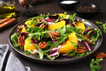 Arugula, orange and pecan salad. Radicchio salad on brown background