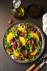 Arugula, orange and pecan salad. Radicchio salad on brown background