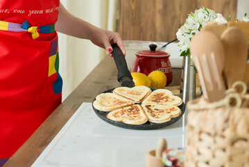 Cooking heart-shaped pancakes in a bright home kitchen